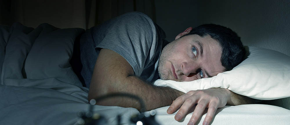 man in bed eyes opened suffering insomnia and sleep disorder